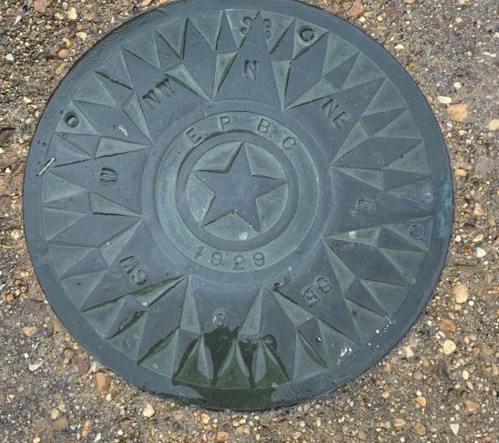 A cast metal compass rose lettered E.P.B.C. and dated 1929, set into the ground at the foot of the clubhouse stairs.